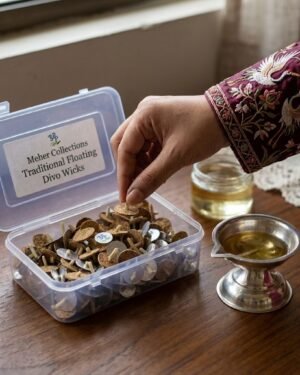 person picking a Meher Collections traditional floating diva wick from a plastic box next to a silver oil lamp.