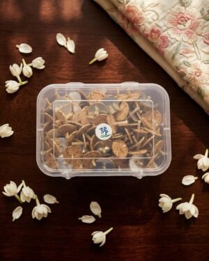 Top-down view of a box of Parsi floating wicks on a wooden surface surrounded by fresh jasmine flowers.