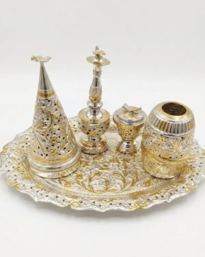 An ornate silver Parsi Sese set with gold floral engravings and filigree work on a white background.