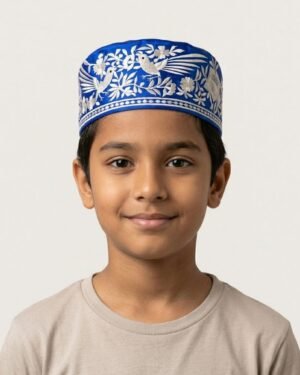 A young boy wearing a royal blue Parsi topi with white nature-inspired Gara embroidery.